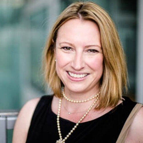 Smiling woman in professional attire outdoors.